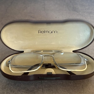 Könnte beinhalten: Eine weiße Keramik-Tasse mit schwarzem Henkel und dem Text "But First, Coffee" in schwarzer, handschriftlicher Schrift. Die Tasse steht auf einer weißen Oberfläche.