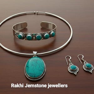 May include: A silver jewellery set with turquoise gemstones. The set includes a necklace, bracelet, pendant, and earrings. The text "Rakhi Jemstone jewellers" is at the bottom of the image.
