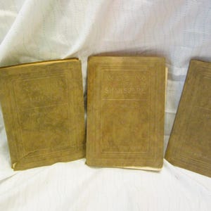 May include: Three rectangular books with tan, textured covers arranged side by side. The center book features the embossed text "AN EVENING WITH SHAKESPEARE" on the front cover. Each book has a simple border design pressed into the material.