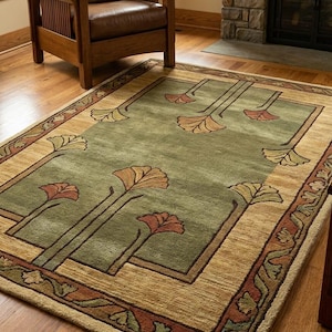 May include: A rectangular area rug featuring a central sage green field decorated with stylized ginkgo leaf motifs in shades of orange and yellow. The rug is framed by a wide tan border and an outer edge patterned with dark brown floral vines.