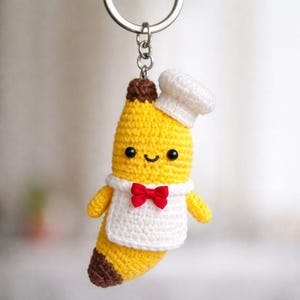 Banankock Amigurumi: Virkad mininyckelring med liten hatt och förkläde, presenttillbehör till matälskare