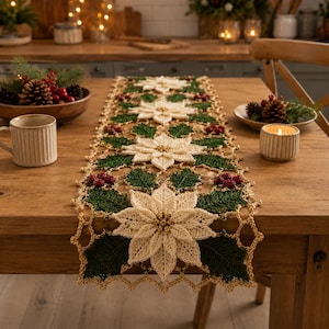 Pode incluir: Um caminho de mesa de crochê com um padrão repetitivo de flores de poinsétia creme, folhas de azevinho verde-escuras e pequenas bagas vermelhas. O caminho tem uma borda festonada em tom dourado sobre uma mesa de jantar de madeira.