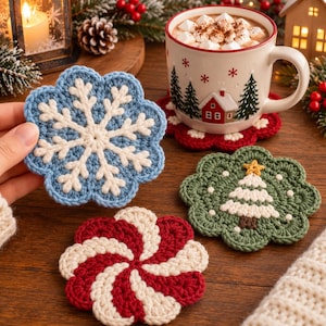 May include: Three round crochet coasters featuring holiday designs: a blue and white snowflake, a green and white Christmas tree with a yellow star, and a red and white peppermint swirl. Each coaster has a scalloped edge and textured surface.