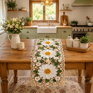 May include: A rectangular crochet table runner featuring a repeating pattern of large white daisies with yellow centers, interspersed with smaller white flowers and green leaves, all set against a light beige, openwork lace background.