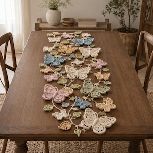 May include: A long, rectangular crochet table runner featuring a delicate, interconnected vine pattern adorned with numerous three-dimensional butterflies in soft pastel shades of pink, blue, yellow, green, and cream, laid flat on a wooden table.