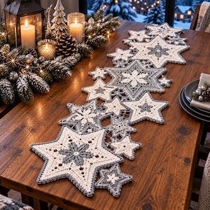 Può includere: Un runner da tavola all'uncinetto con una serie di motivi a stella e fiocco di neve interconnessi in filato color crema e grigio. Il runner è composto da stelle di varie dimensioni disposte in un motivo lineare con punti complessi.