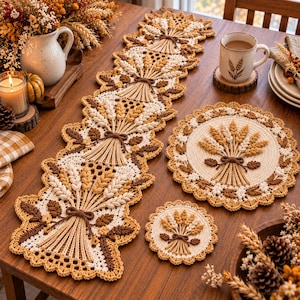 May include: A crochet table runner, a round placemat, and a small coaster, all featuring a wheat sheaf motif in shades of cream, tan, and brown. The pieces have intricate scalloped edges and are crafted with a textured, yarn-based construction.