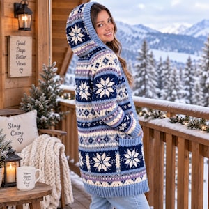 May include: A long-sleeved hooded cardigan featuring a repeating pattern of white snowflakes on a dark blue, light blue, and lavender background. The knit garment includes a hood, two front pockets, and ribbed cuffs, showcasing a detailed winter-themed design.