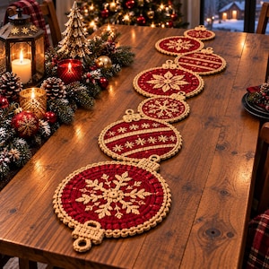 May include: A crochet table runner featuring a series of connected circular ornaments in deep red and cream. Each ornament displays intricate snowflake or striped patterns with a textured border, laid out linearly across a wooden dining table surface.