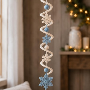 May include: A hanging spiral decoration featuring a cream-colored crocheted cord intertwined with alternating light blue and cream crocheted spheres and intricate crocheted snowflake ornaments in matching light blue and cream colors.