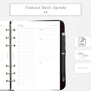 May include: An open A5 undated daily agenda with a black pen. The agenda has sections for priorities, to-do lists, and notes. The top of the page reads "Undated Daily Agenda A5". The agenda is held in a brown leather binder.