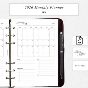 May include: A 2026 monthly planner with a January calendar page open. The planner is A5 size and includes sections for priorities, to-do lists, and important dates. A black pen rests on the right side. The words "2026 Monthly Planner" and "Printable" are visible.