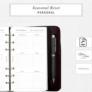 May include: A planner with the text "Seasonal Reset PERSONAL" at the top. The open planner shows lined pages with prompts for seasonal focus, intentions, activities, refresh, let go, and reflections. A black pen rests on the right side. A PDF icon and the words "Paper Dove DESIGNS PRINTABLE" are visible.