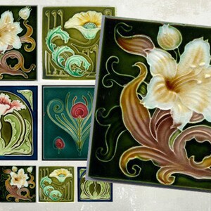 Puede incluir: Un conjunto de nueve azulejos de cerámica vintage con un diseño floral. Los azulejos son verdes, marrones y blancos con un patrón floral estilizado. Los azulejos son perfectos para agregar un toque de encanto vintage a cualquier hogar.