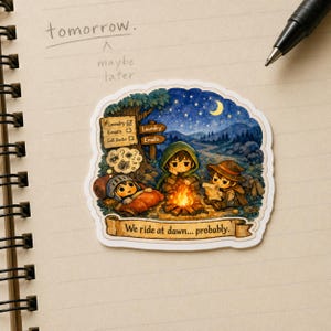 May include: A charming sticker depicting three cartoon characters camping by a fire under a starry sky. The sticker includes the text "We ride at dawn... probably." and a checklist with "Laundry" and "Emails."