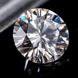 May include: A round, brilliant-cut diamond with numerous facets, reflecting light and creating a sparkling effect. The gemstone is set against a black background, highlighting its clarity and brilliance. The diamond's shape is perfectly symmetrical.