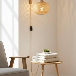 Könnte beinhalten: Eine gewebte Pendelleuchte aus Rattan hängt an einem Holzbogen an der Wand. Ein kleiner Beistelltisch hält gefaltete Handtücher und eine Topf-Sukkulente. Ein Stuhl in neutralen Tönen steht in der Ecke.