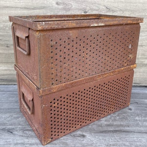 May include: Two stacked metal storage boxes with a rusty brown finish. The boxes have a perforated design and are made of metal.