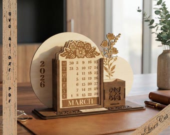 May include: A wooden desk calendar for March 2026, featuring a floral design and a small pen holder. The calendar is made of light and dark brown wood. The text "2026" is visible on a circular wooden piece. The words "SVG AI DXF PDF" are on the side.