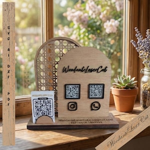 Könnte beinhalten: Ein Holzständer mit dem Text "WoodanteLaserCut" und zwei QR-Codes. Der Ständer verfügt außerdem über Social-Media-Symbole und Kontaktinformationen. Eine kleine Sukkulente in einem Terrakotta-Topf steht daneben.