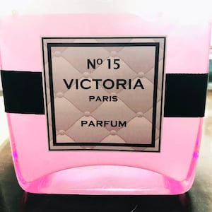 May include: A pink glass bottle with a black and silver label that reads "No 15 VICTORIA PARIS PARFUM".
