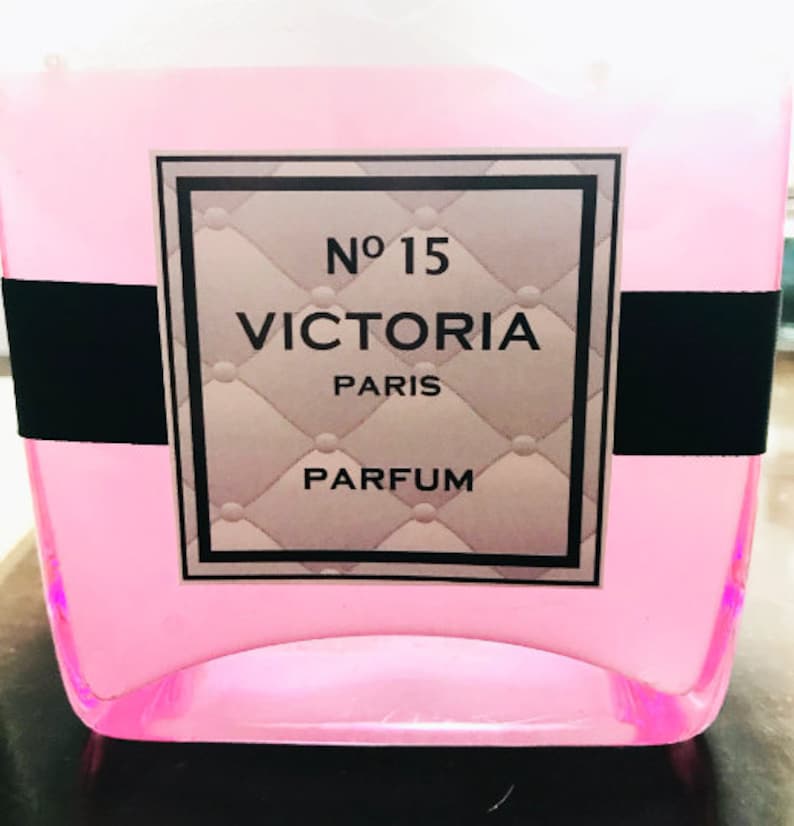 May include: A pink glass bottle with a black and silver label that reads "No 15 VICTORIA PARIS PARFUM".