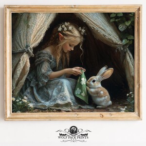 May include: A framed print depicts a young woman with pointed ears, wearing a blue dress, seated inside a tent-like structure. She interacts with a brown and white rabbit, holding a green cloth with white floral designs. The artwork has a fairytale theme.