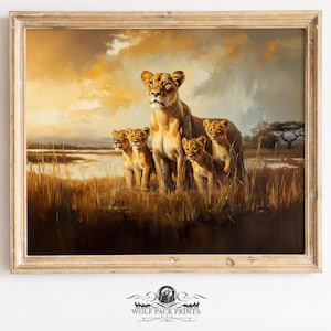 May include: A framed print of a lioness and her cubs in a savanna landscape. The artwork uses a warm colour palette of golden yellows and browns, with the lions standing in tall grass. The print is from Wolf Pack Prints.