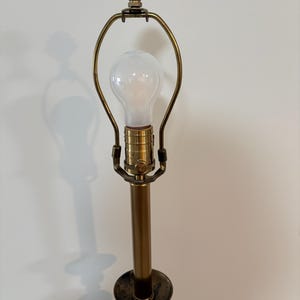 Puede incluir: Una l&aacute;mpara de mesa de lat&oacute;n vintage con un remate en forma de concha. La l&aacute;mpara presenta una bombilla, un largo v&aacute;stago de lat&oacute;n y una base decorativa. El dise&ntilde;o de la l&aacute;mpara es cl&aacute;sico y elegante.