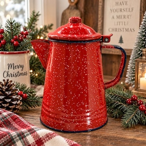 May include: A bright red enamel coffee pot featuring a white speckled pattern throughout its surface. The pot has a matching lid, a curved spout, and a dark blue rimmed handle. The design is cylindrical with a slightly tapered top section.