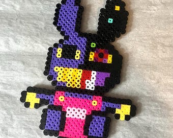 May include: A pixel art bunny figure made from colorful plastic beads. The bunny has purple ears and body, a pink torso, and black accents. The eyes are yellow and red. The arms and feet are yellow.