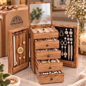May include: A wooden jewelry box with a vertical mirror, four pull-out drawers, and two side panels for hanging necklaces and earrings. The box features a natural wood grain finish, small metal knobs, and interior compartments filled with various rings, necklaces, and earrings. The HANGARHUB logo is printed on the side of the box and on a gold pendant.