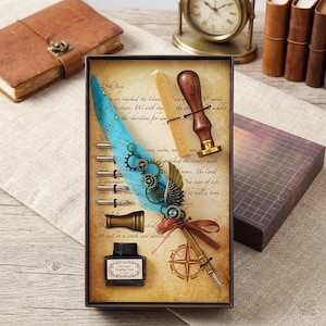 Op de afbeelding: Een vintage schrijfgarnituur in een decoratieve doos. De set bevat een blauwe ganzenveerpen met tandwielen, inktfles, zegel en kompasontwerp. De doos heeft een perkamentachtige achtergrond met tekst.