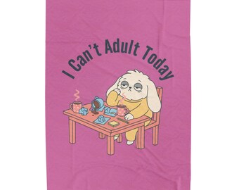 May include: A pink blanket featuring a cartoon illustration of a tired white dog sitting at a table with coffee mugs and crumpled paper. The text "I Can't Adult Today" is printed in dark grey above the dog, who wears a yellow shirt.