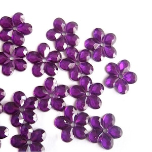 May include: Purple flower-shaped embellishments, perfect for adding a touch of sparkle to crafts and decorations.