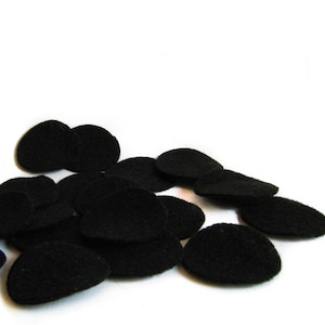 May include: A pile of black felt circles, scattered on a white background.