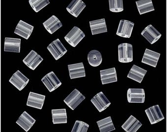 May include: A collection of clear, cylindrical earring backs scattered on a black background. The earring backs are made of a transparent material and have a small hole running through the center. The image is well-lit, highlighting the details of each earring back.