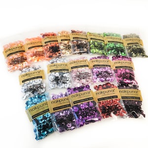 May include: Assortment of 16 small bags of flower-shaped sequins in various colors, including silver, gold, pink, red, purple, blue, green, and black. Each bag has a label with the text "nakpunar" and a website address.