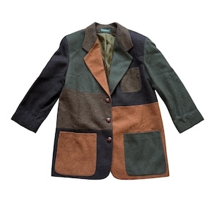 Puede incluir: Un blazer de bloques de color con un diseño de patchwork en tonos marrón oscuro, verde oliva y naranja óxido. Esta chaqueta de manga larga tiene solapa de muesca, tres botones frontales, un bolsillo en el pecho y dos bolsillos grandes.