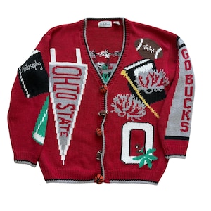 May include: A red V-neck knit cardigan featuring various embroidered and knit-in designs including an Ohio State pennant, a football, a book labeled Philosophy, the letter O, and the text GO BUCKS. The buttons are shaped like small sports balls.