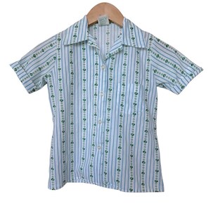May include: A short-sleeved shirt with a white and blue striped design, featuring green heart-shaped patterns. The shirt has a collared neckline, a single chest pocket, and is fastened with buttons. The shirt is suitable for casual wear.