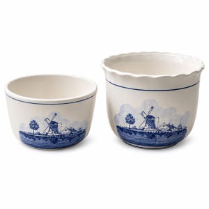 May include: Two white ceramic bowls featuring a blue painted landscape design of a windmill, trees, and houses. The bowls have a smooth finish with a thin blue line circling the upper rim and a scalloped edge on the larger bowl.