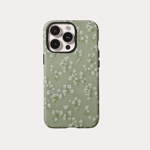 May include: A sage green smartphone case featuring a repeating pattern of small white flowers with thin green stems. The case has a rectangular cutout at the top left corner for a triple-lens camera system and a black border around the lens area.