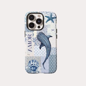 Puede incluir: Una funda para teléfono con un diseño de patchwork en azul y blanco con varios patrones, una ilustración central de tiburón ballena, una estrella de mar azul, una concha y la palabra AMOR impresa verticalmente en un bloque blanco a la izquierda.