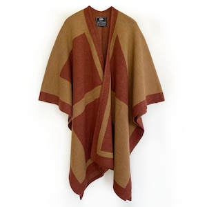 Puede incluir: Un poncho con estampado geométrico en tonos marrón y óxido. El poncho presenta un diseño de cuello en V y un patrón rectangular en la parte delantera y trasera. Los bordes están ribeteados con un borde marrón más oscuro. La prenda se muestra sobre un fondo blanco.