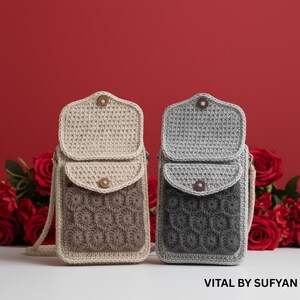 Peut inclure: Deux sacs de téléphone en crochet beige et gris, avec une fermeture à rabat et un motif en nid d'abeille texturé sur le devant. Chaque sac a une fermeture à bouton en bois et une longue sangle. Texte: VITAL BY SUFYAN.