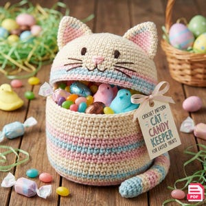 Könnte beinhalten: Ein gehäkelter, katzenförmiger Süßigkeitenbehälter, gefüllt mit bunten Süßigkeiten und Marshmallow-Küken. Der Behälter ist cremefarben mit rosa und blauen Streifen und trägt ein Etikett mit der Aufschrift "Cat Candy Keeper for Easter Treats."