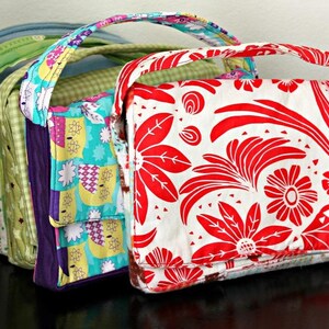 May include: A collection of colorful, handmade fabric tote bags. The bags feature various patterns, including floral, geometric, and patchwork designs. Each bag has a matching handle and a rectangular shape, perfect for carrying essentials. The bags are displayed in a row, showcasing their unique designs.