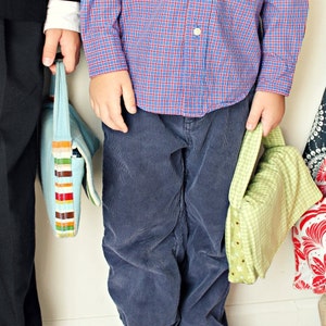 May include: Three children holding colorful tote bags. The bags have various patterns, including stripes, floral, and geometric designs. The children are wearing different outfits, including a dress, pants, and a button-down shirt.