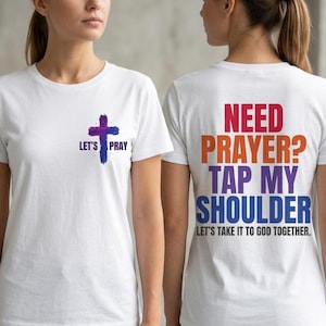 May include: White t-shirts with text and a cross graphic. One shirt has a cross and the words "LET'S PRAY". The other shirt says "NEED PRAYER? TAP MY SHOULDER" with the phrase "LET'S TAKE IT TO GOD TOGETHER."